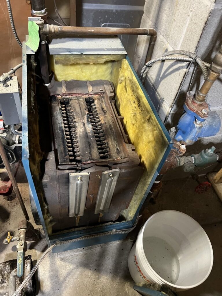 The dirty interior of an old boiler with the cover removed, showing components needing cleaning or repair by HomeStyle Heating and Air LLC in Barrington, NH.