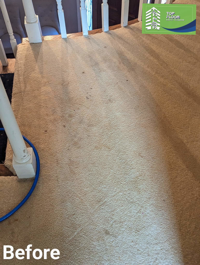 A wide view of a dirty, light-colored carpeted area at the top of stairs, labeled 'Before' cleaning by Top Floor Carpet Cleaning in Lenoir City, TN.