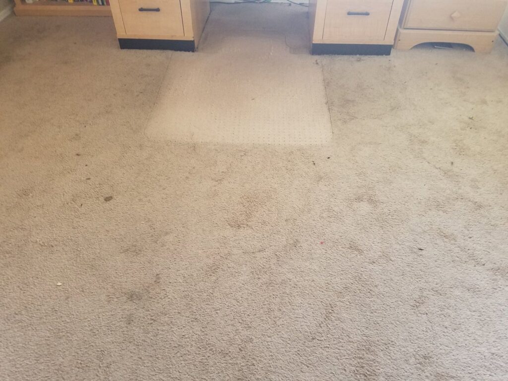A dirty carpet under a desk with a noticeable clean patch by Integrity Cleaning Systems in Peoria, AZ