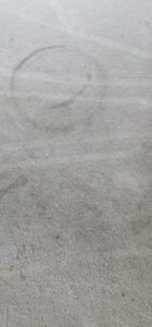 A close-up of a dirty carpet with a visible circular stain, before cleaning by BEST Professionals Cleaning, LLC in Lancaster, PA
