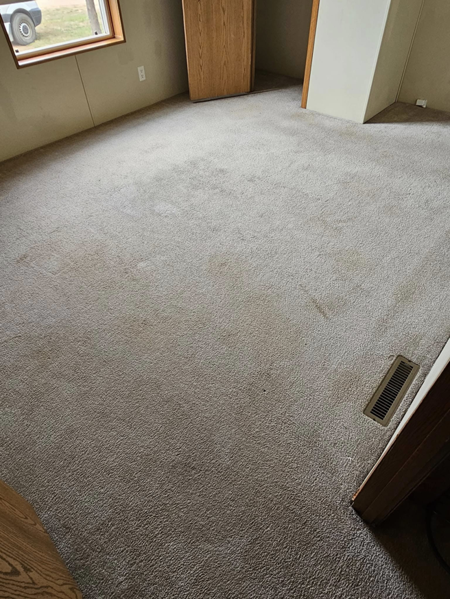 A dirty carpeted room with visible spots, before cleaning by Peterson's Carpet & Air Duct Cleaning in Dickinson, ND.