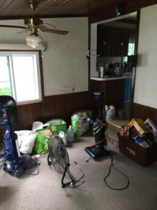 A dirty carpeted room with two vacuum cleaners, indicating a carpet cleaning job by A Little More Martha, LLC in Lansing, MI.