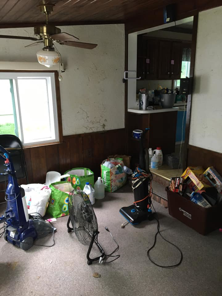 A dirty carpeted room with two vacuum cleaners, indicating a carpet cleaning job by A Little More Martha, LLC in Lansing, MI.
