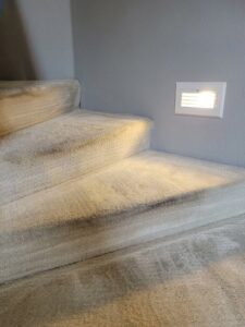 A carpeted staircase showing signs of dirt and wear, awaiting cleaning by Pacific Steam Carpet Cleaning in Gresham, OR.
