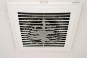 A dirty ceiling air vent or grille, heavily caked with dust, indicating the need for duct cleaning by Air Doctor Duct Cleaning & Lining in Tulsa, OK.
