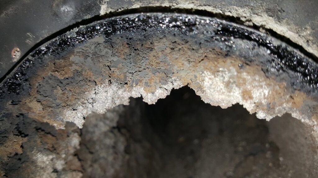 A close-up view inside a dirty chimney flue showing significant creosote buildup, indicating a need for sweeping by Chimney Karma in Fort Collins, CO.