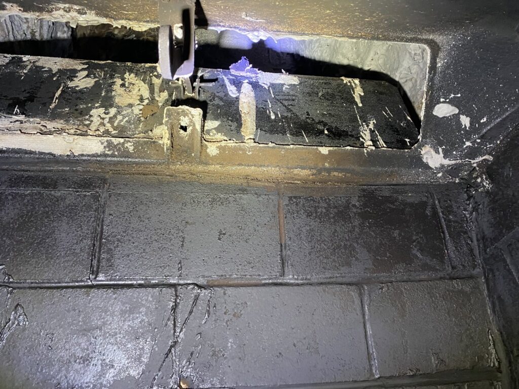 The dirty interior of a chimney flue and damper, showing the need for a professional chimney sweep by HBR Hearth and Chimney in Dallas, TX