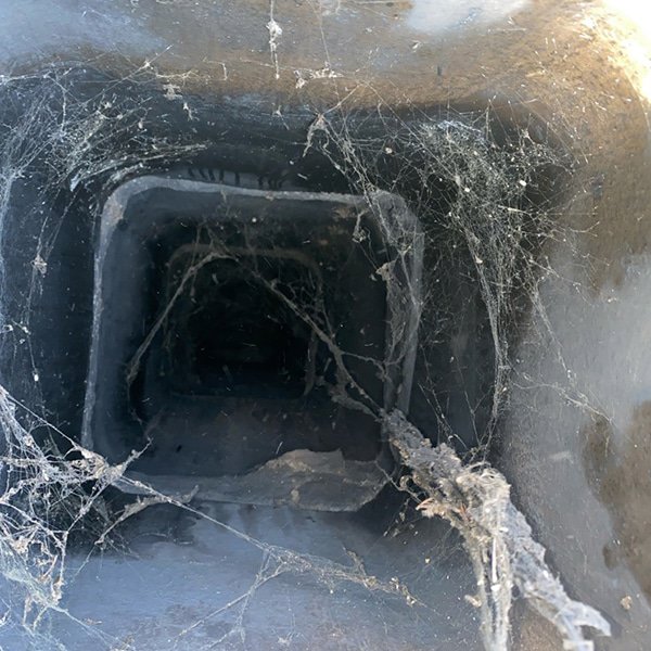 A view looking down into a dirty chimney flue filled with cobwebs and debris, indicating a need for sweeping by A Sweep Across the Bay in Parrish, FL.