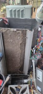 A heavily dirty and clogged outdoor AC coil requiring cleaning, inspected by Nelke Mechanical in Keizer, OR.
