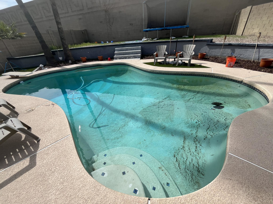 A dirty and cloudy swimming pool with debris on the bottom, indicating a need for service from Brigade Pool Services in Tempe, AZ.