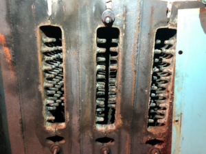 A close-up of a dirty and corroded furnace heat exchanger, an HVAC issue addressed by EH Gochnauer & Sons, Inc. in Lancaster, PA.