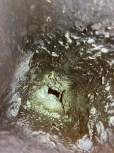 A close-up view inside a dirty, creosote-filled chimney flue, showing the need for a sweep by Heartland Chimney Sweeps LLC in McCall, ID.
