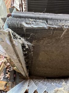 A close-up view of a very dirty and damaged outdoor AC coil requiring service from American Air LLC in Moncks Corner, SC