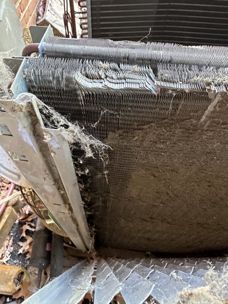 A close-up view of a very dirty and damaged outdoor AC coil requiring service from American Air LLC in Moncks Corner, SC