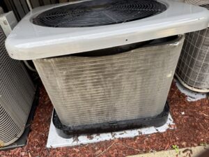 A dirty or damaged outdoor AC condenser unit, indicating a need for HVAC service from Etek Refrigeration Heating and Cooling, Inc. in Chicago, IL.