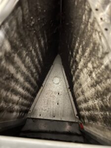 A very dirty evaporator coil inside an air handler, showing the need for professional cleaning from Simply Home Service in Gaithersburg, MD.
