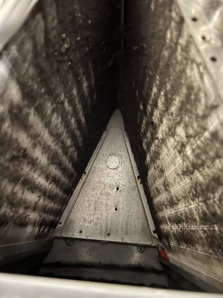 A very dirty evaporator coil inside an air handler, showing the need for professional cleaning from Simply Home Service in Gaithersburg, MD.