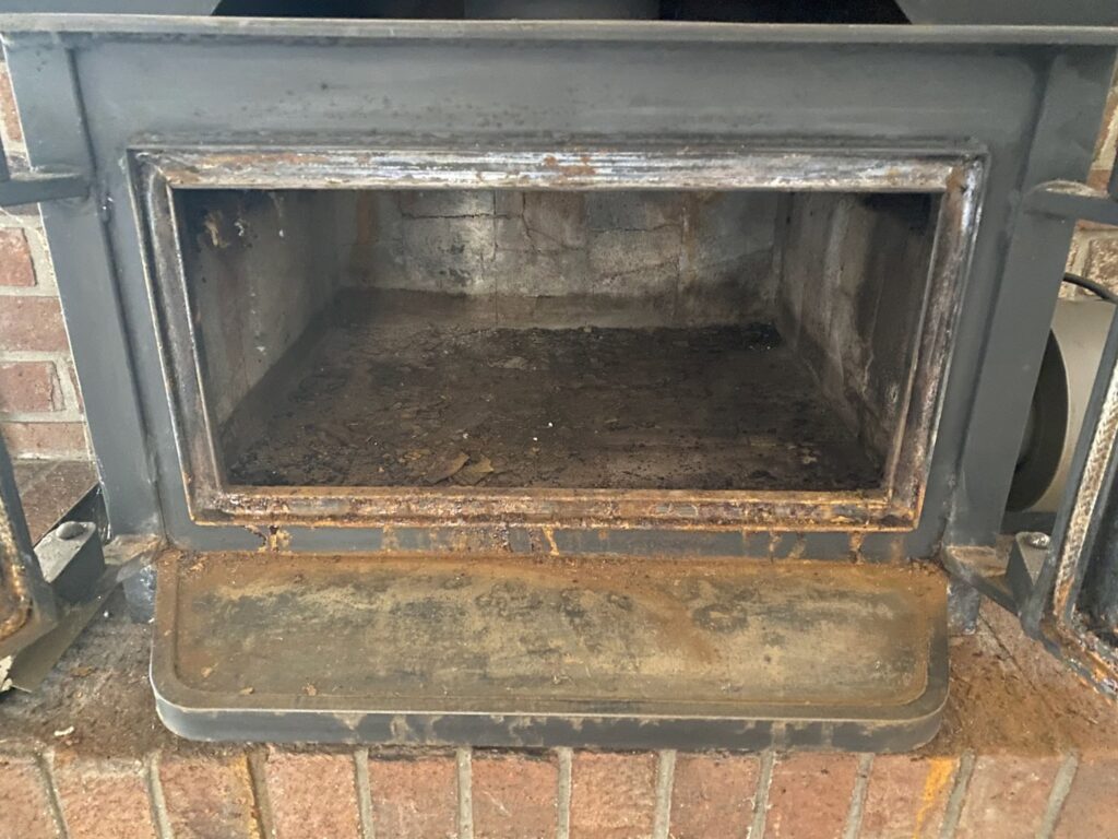 An empty, dirty fireplace insert ready for cleaning by Chimney Cricket Cleaning Service in Marshfield, MO
