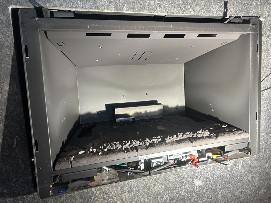 A very dirty fireplace insert filled with ash and debris, ready for a professional chimney sweep by Local Chimney Services LLC in Providence, MA.