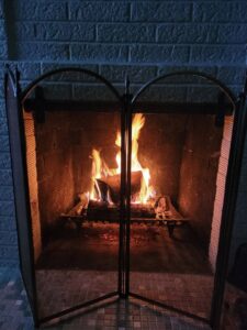 A dirty fireplace with a large pile of soot and a vacuum hose, indicating a chimney sweep job by Chimney Mechanix of Indiana in Lafayette, IN.