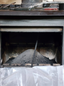 A dirty fireplace with a large pile of ash and soot, indicating a need for chimney sweep services by Chimney Wizards LLC in Orofino, ID.