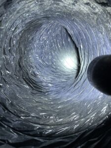 A view inside a dirty flexible air duct with accumulated dust, before cleaning by Vacman Air Duct Cleaning in South Bend, IN