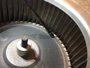 A close-up view of a dirty furnace blower wheel, highlighting the need for HVAC cleaning from Waymaker HVAC LLC in Colorado Springs, CO.