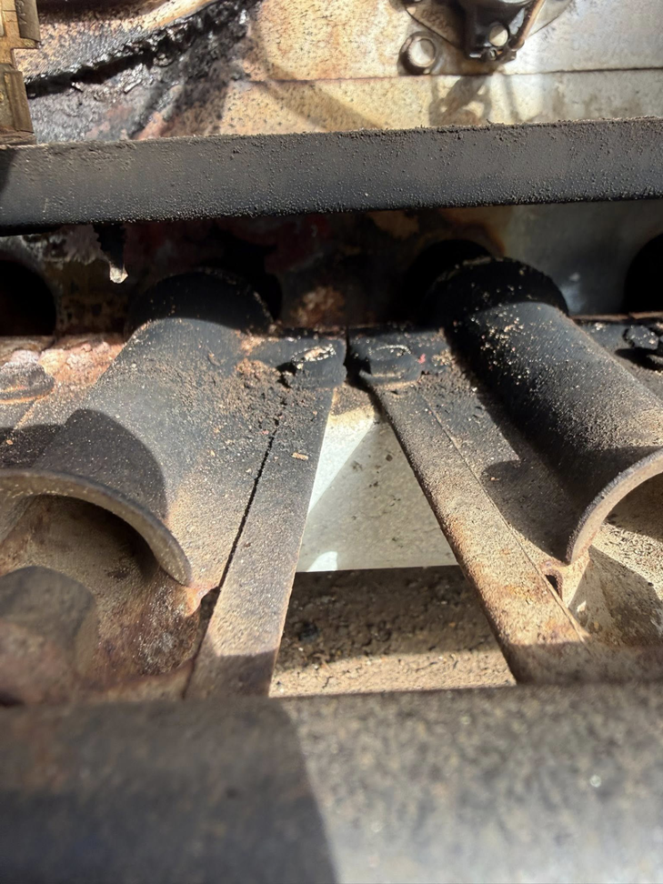 Close-up of dirty furnace burner tubes requiring service from Freedom Heating & Cooling in Lathrop, MO.