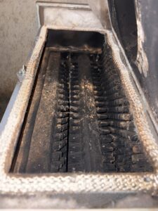 A dirty furnace heat exchanger covered in soot and ash, ready for cleaning by Black Oak HVAC in Derry, NH