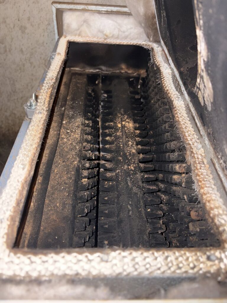 A dirty furnace heat exchanger covered in soot and ash, ready for cleaning by Black Oak HVAC in Derry, NH