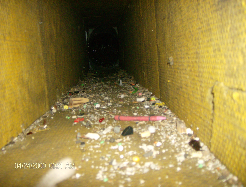 Interior view of a dirty HVAC air duct filled with debris, indicating a need for cleaning by Air Essentials in Madison, AL