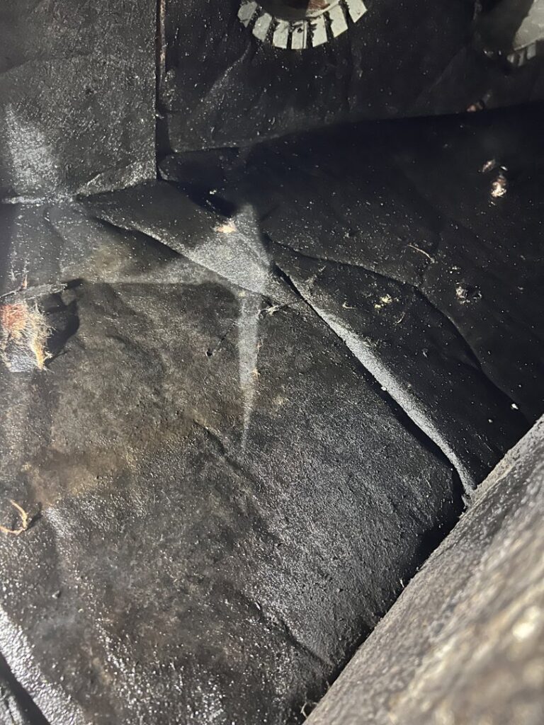 The interior of a dirty HVAC air duct, showing accumulated dust and debris, ready for cleaning by AirHero.Pro in Lafayette, LA.