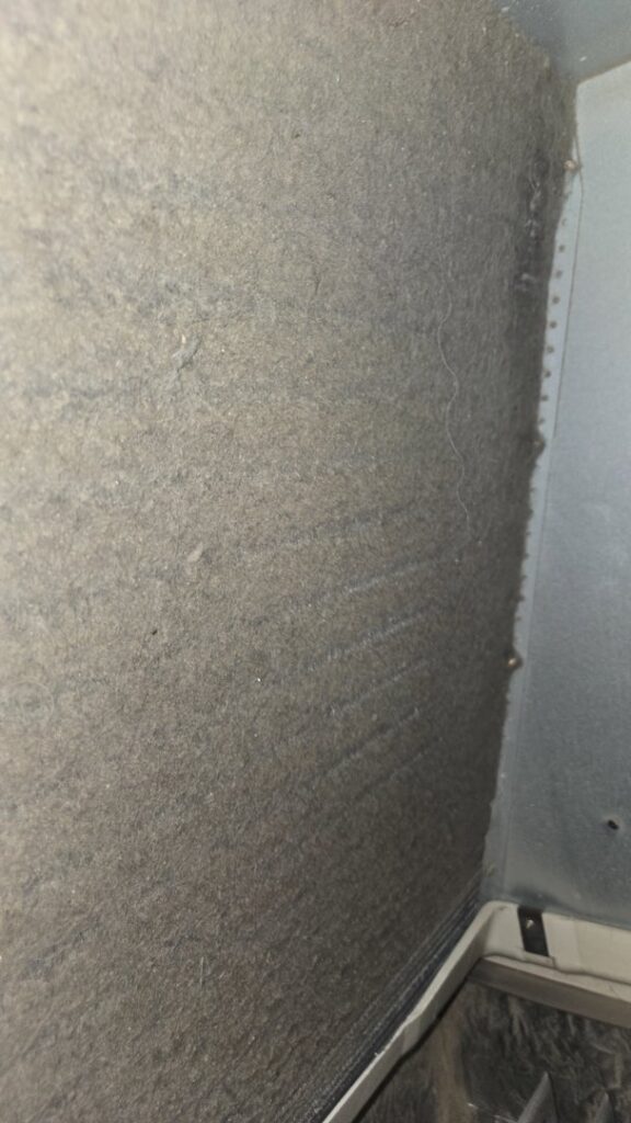 A close-up of a very dirty HVAC air filter or duct interior, showing dust buildup by Precision Vac in Thornton, CO.