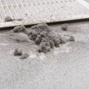 A dirty HVAC air filter with a pile of dust, indicating a need for cleaning or replacement by GreenSerbiz in Los Angeles, CA