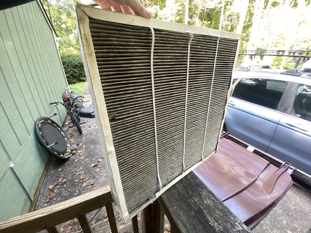 A technician holding up a very dirty HVAC air filter, showing the need for maintenance by Lee Air Conditioning in Lafayette, LA.