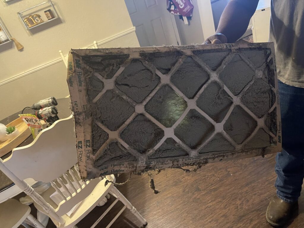 An extremely dirty HVAC air filter being held up, demonstrating the need for regular replacement by Chill Out Heating and Cooling in Tulsa, OK.