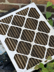 A heavily soiled HVAC air filter ready for replacement by Custom Comfort RVA in Richmond, VA.