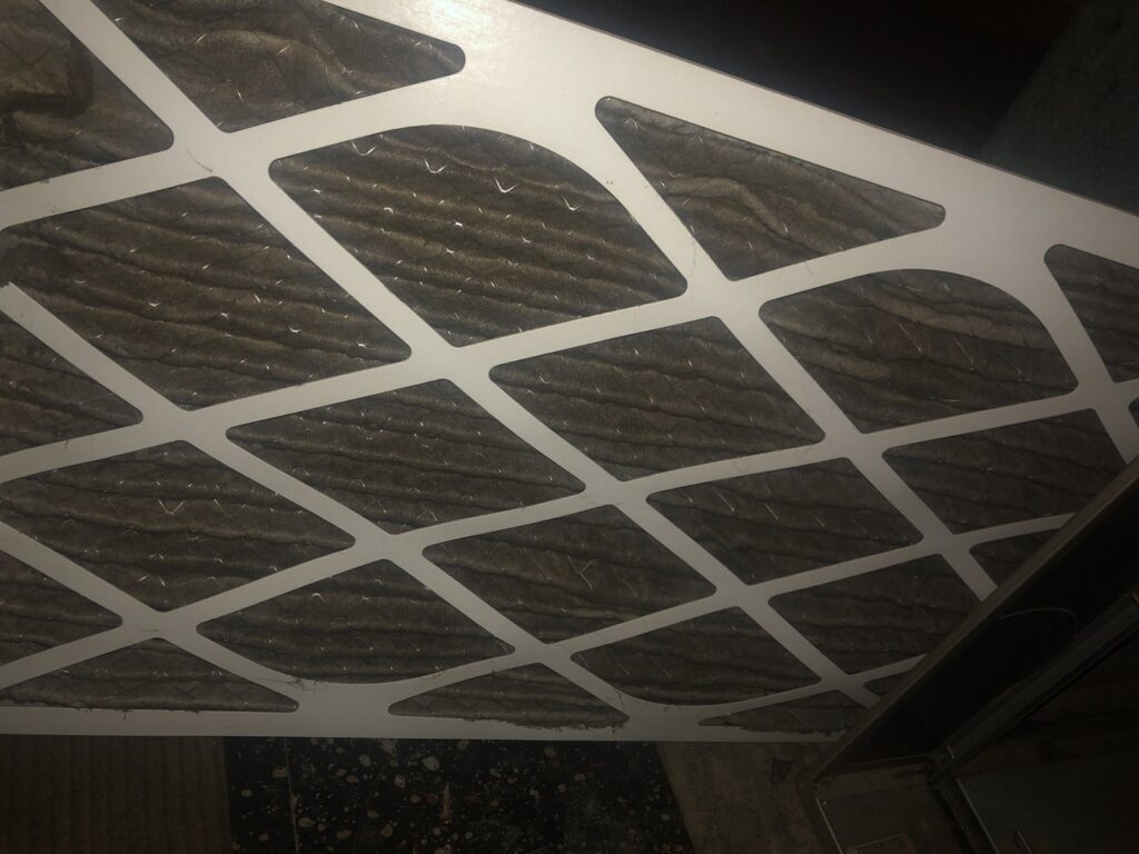 A very dirty HVAC air filter needing replacement, indicating maintenance by Elements Heating & Cooling LLC in Minneapolis, MN.