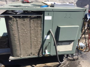 A dirty outdoor HVAC condenser unit on a rooftop, showing the need for service from Corbe Heating and Air Conditioning in Elgin, IL.