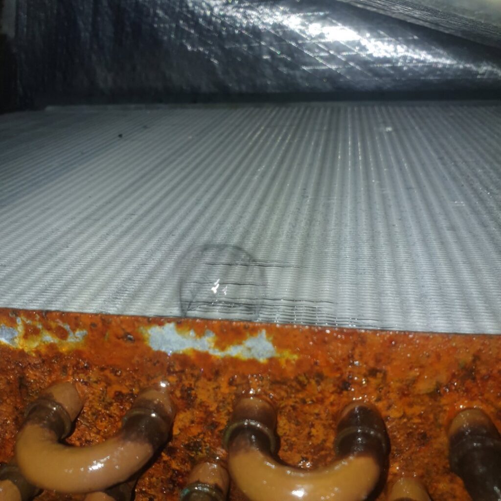 A close-up view of a dirty and rusty HVAC evaporator coil requiring service from Home Shield Heating and Air in Shreveport, LA.