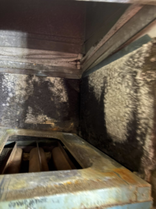 A close-up view of a dirty HVAC unit interior, showing grime and potential mold, serviced by Pepper Mechanical in Pittsburgh, PA