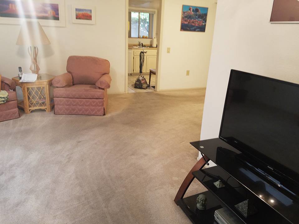 A dirty living room carpet with a vacuum cleaner, ready for cleaning by Integrity Cleaning Systems in Peoria, AZ