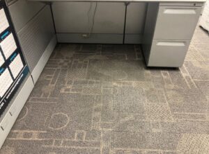 An office carpet under a desk, showing wear and dirt before cleaning by Olen's Carpet & Upholstery Cleaning LLC in Cleveland, OH.