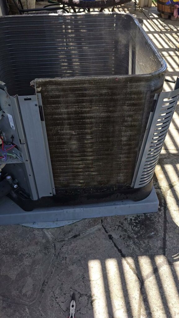 An outdoor air conditioning unit with dirty coils exposed, indicating a need for maintenance from Ecology Air Innovations in Sacramento, CA.