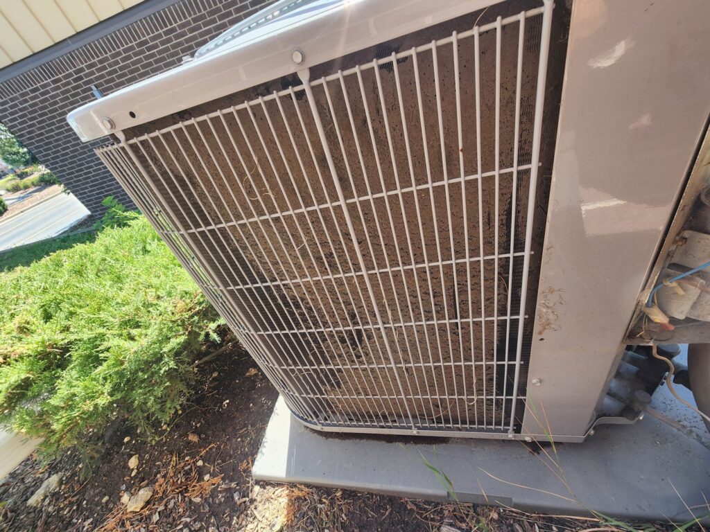 A dirty outdoor AC condenser coil indicating a need for cleaning or maintenance from Service Champions Heating & Cooling in Aurora, IL.