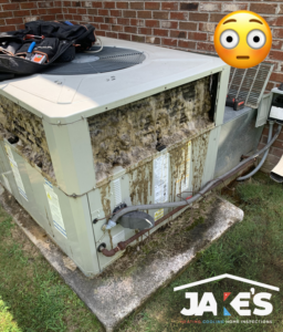 A severely dirty outdoor AC condenser unit requiring maintenance from Jake's Heating and Cooling in Buffalo, NY.