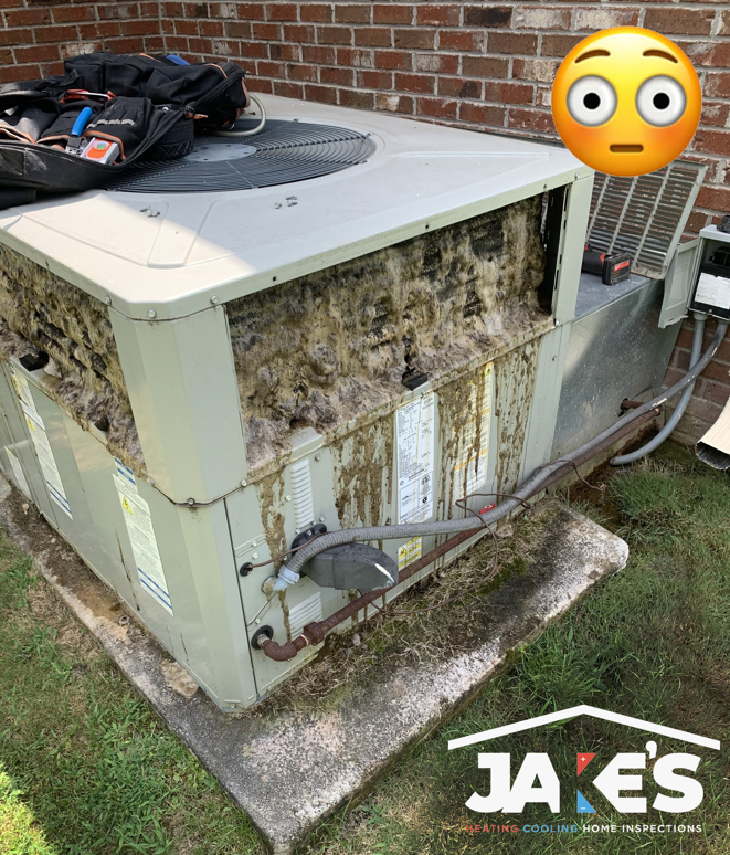 A severely dirty outdoor AC condenser unit requiring maintenance from Jake's Heating and Cooling in Buffalo, NY.