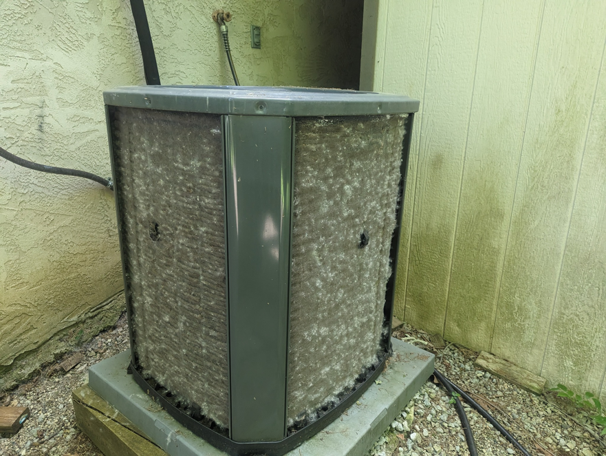 A heavily soiled outdoor AC condenser unit requiring cleaning and maintenance from Polaris Heating and Cooling in Columbus, OH.