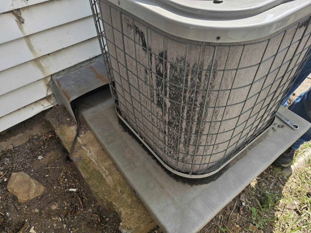 A dirty outdoor AC condenser unit in need of cleaning or service by ReDesign Air in Winchester, VA.