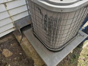 A dirty outdoor AC condenser unit in need of cleaning or service by ReDesign Air in Winchester, VA.